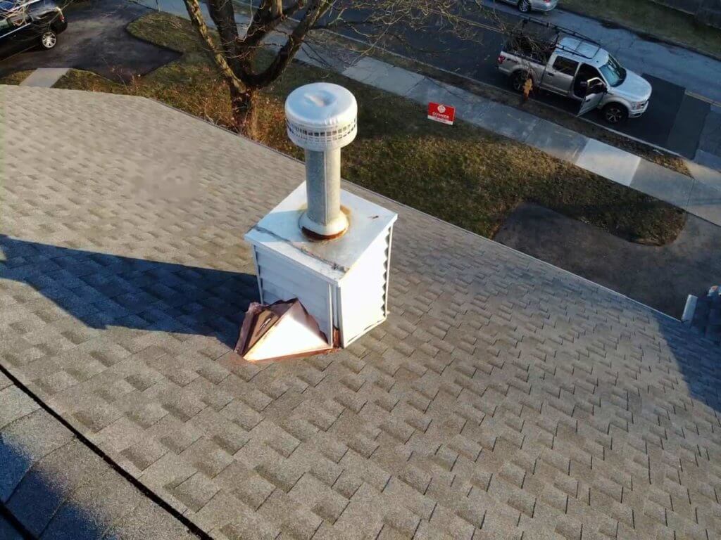 View of roof with asphalt shingles and chimney