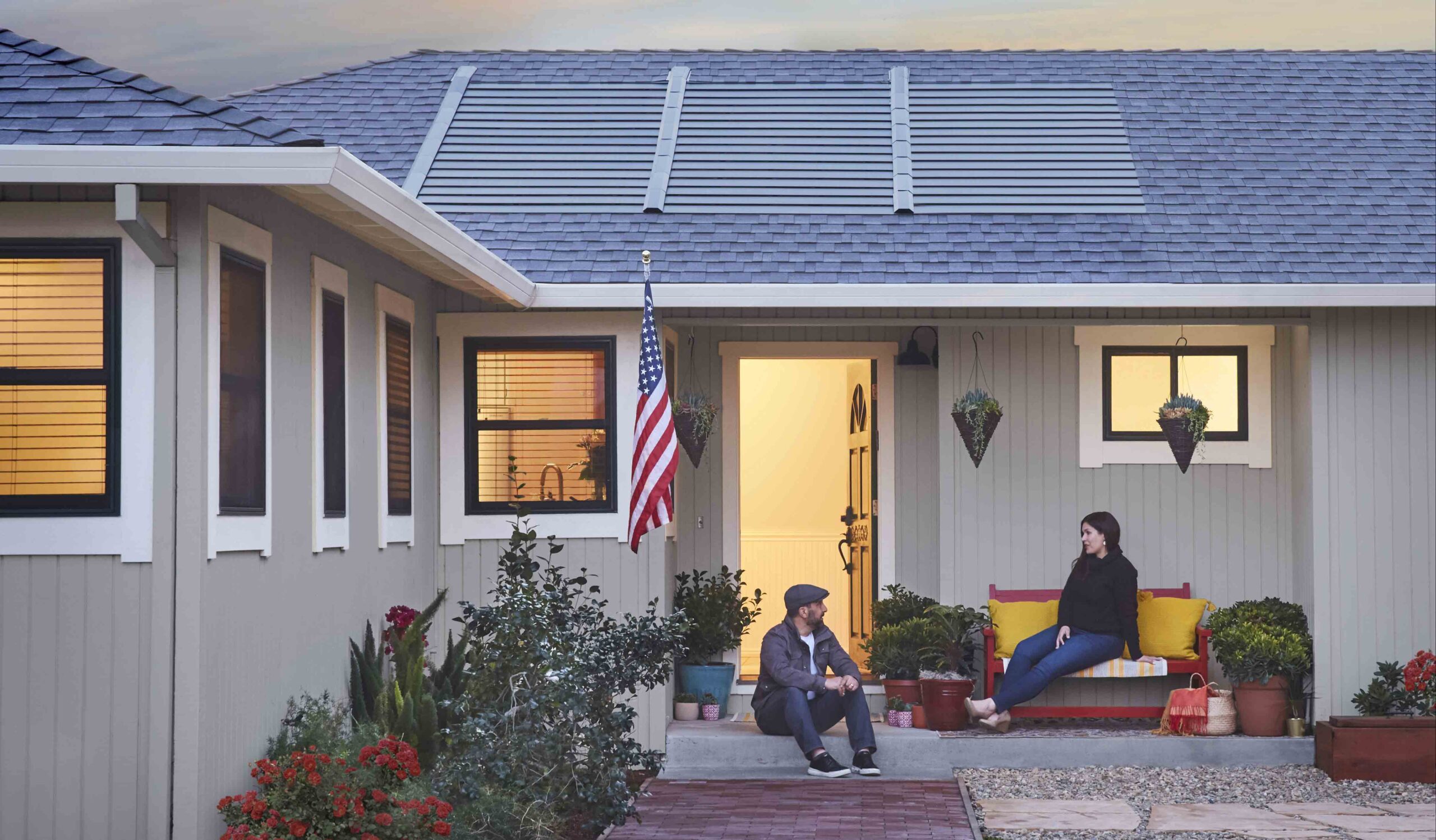 Couple sitting on back porch of home with GAF Timberline solar shingles