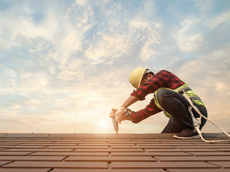 Contractor working on roof at sunrise