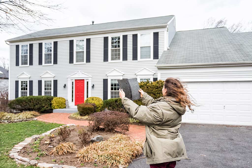 Customer holding up shingle samples in front of home